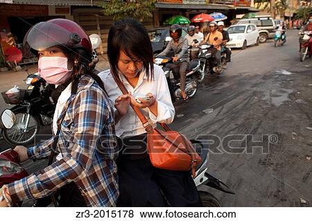 A young woman text from the back of a motorbike in Phnom Penh, Cambodia. View Large Photo Image Stock Photo - A young woman text from the back of a motorbike in Phnom Penh, Cambodia.. Fotosearch