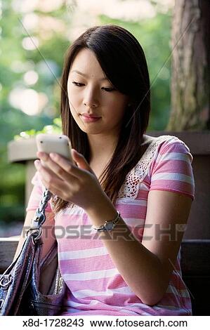 A young woman texting on her mobile phone View Large Photo Image Stock Image - A young woman texting on her mobile phone. Fotosearch