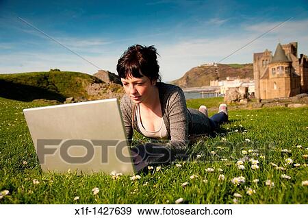 A young woman UK Aberystwyth university student working on her apple laptop computer outdoors on a sunny warm day View Large Photo Image Stock Photo - A young woman UK Aberystwyth university student working on her apple laptop computer outdoors on a sunny warm day. Fotosearch