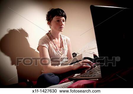 A young woman UK university student working on her laptop computer in her bedroom at home View Large Photo Image Stock Image - A young woman UK university student working on her laptop computer in her bedroom at home. Fotosearch