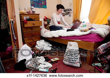 A young woman UK university student working on her laptop computer on the bed in an untidy bedroom View Large Photo Image Stock Photograph - A young woman UK university student working on her laptop computer on the bed in an untidy bedroom. Fotosearch