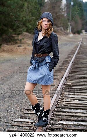 Stock Image - A young woman walking on train tracks. Fotosearch