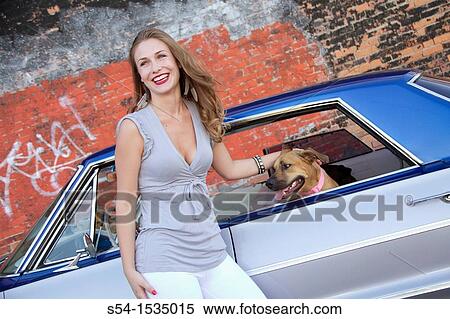 Stock Photography - A young woman with a 1964 Chevrolet Impala in Spokane, Washington, USA.. Fotosearch