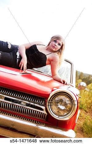 Stock Photo - A young woman with a red 1964 Dodge Dart.. Fotosearch