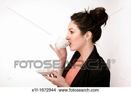 A young woman with brown hair and eyes drinking tea from a dainty cup and saucer View Large Photo Image Picture - A young woman with brown hair and eyes drinking tea from a dainty cup and saucer. Fotosearch
