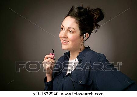 A young woman with brown hair and eyes listening top music on her small iPod Nano MP3 player View Large Photo Image Stock Image - A young woman with brown hair and eyes listening top music on her small iPod Nano MP3 player. Fotosearch