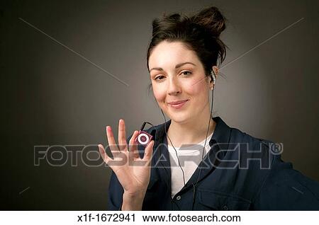 A young woman with brown hair and eyes listening top music on her small iPod Nano MP3 player View Large Photo Image Stock Image - A young woman with brown hair and eyes listening top music on her small iPod Nano MP3 player. Fotosearch