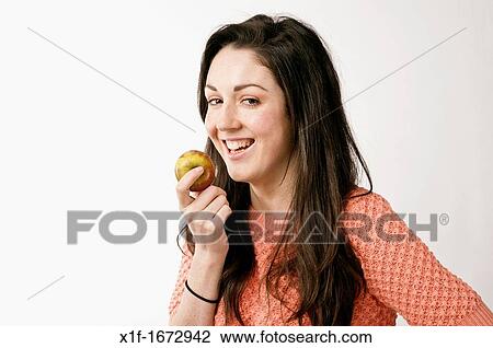 A young woman with brown hair and eyes eating an apple View Large Photo Image Stock Image - A young woman with brown hair and eyes eating an apple. Fotosearch