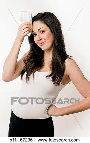 Stock Image - A young woman with brown hair and eyes drinking a glass of cold milk. Fotosearch