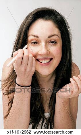 A young woman with brown hair and eyes applying her makeup eyeliner View Large Photo Image Stock Image - A young woman with brown hair and eyes applying her makeup eyeliner. Fotosearch
