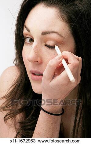 A young woman with brown hair and eyes applying her makeup eyeliner View Large Photo Image Stock Image - A young woman with brown hair and eyes applying her makeup eyeliner. Fotosearch