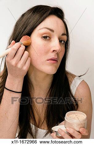 A young woman with brown hair and eyes applying her face blusher powder makeup View Large Photo Image Stock Photograph - A young woman with brown hair and eyes applying her face blusher powder makeup. Fotosearch