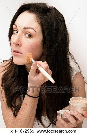 A young woman with brown hair and eyes applying her face blusher powder makeup View Large Photo Image Stock Photography - A young woman with brown hair and eyes applying her face blusher powder makeup. Fotosearch