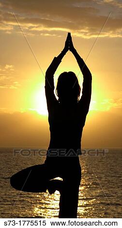 Stock Photography - A young women practises the art of Yoga over a beautiful sunset at Tenerife beach. Fotosearch