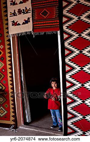 A young Zapotec indigenous girl smiles as she peaks out of a doorway at her families carpet weaving workshop October 30, 2013 in Teotitlan de Valle, Mexico. View Large Photo Image Picture - A young Zapotec indigenous girl smiles as she peaks out of a doorway at her families carpet weaving workshop October 30, 2013 in Teotitlan de Valle, Mexico.. Fotosearch