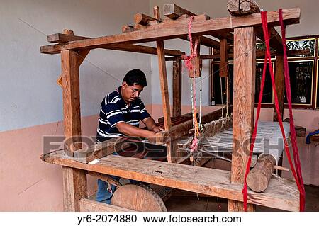 Stock Image - A Zapotec indigenous man uses a hand loom to weave traditional carpets October 30, 2013 in Teotitlan de Valle, Mexico.. Fotosearch