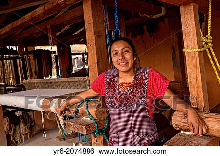 Stock Photograph - A Zapotec indigenous woman poses in front of her hand loom used to weave traditional carpets October 30, 2013 in Teotitlan de Valle, Mexico.. Fotosearch
