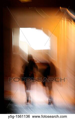 Stock Photograph - abstract two people walking in dark corridor at night. Fotosearch
