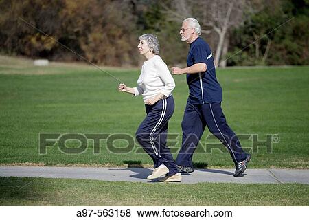 Stock Photo - Active senior couple in exercise clothes jogging in an outdoor park.. Fotosearch