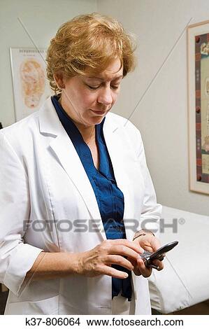 Acupuncturist using her cell phone View Large Photo Image Picture - Acupuncturist using her cell phone. Fotosearch