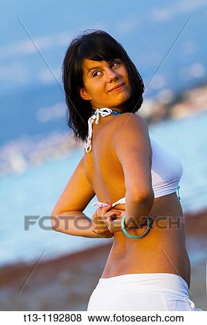 Stock Photo - Adjusting her swimsuit bra behind back. Fotosearch