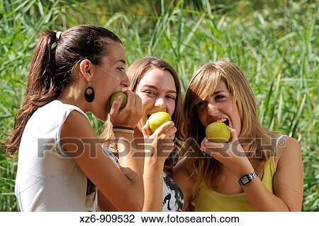 Stock Image - Adolescents eating apple in the park. Fotosearch