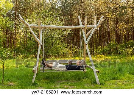 Adult man reading an eBook while lying on a swing. View Large Photo Image Stock Image - Adult man reading an eBook while lying on a swing.. Fotosearch