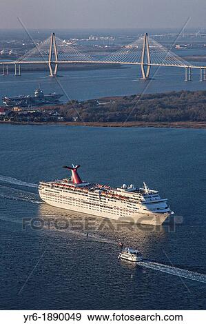 Stock Photo - Aerial showing Carnival Cruise Lines ship departing Charleston Harbor with the Ravenel Bridge in the background in Charleston, SC. Fotosearch