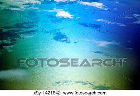 Stock Image - aerial view of calm blue sea ocean texture surface with clouds, shadows and islands. Fotosearch