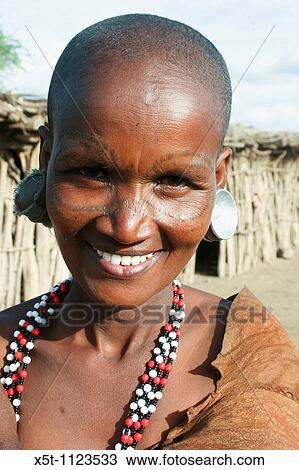 Stock Image - Africa, Tanzania, female members of the Datoga tribe Woman in traditional dress, beads and earrings Beauty scarring can be seen around the eyes, April 2008. Fotosearch
