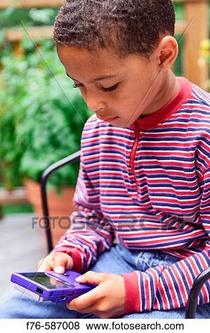 Stock Photo - African American boy playing with hand held computer game.. Fotosearch