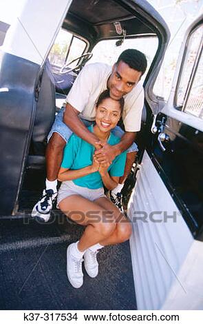 Picture - African American couple sitting inside their 1950's truck. Fotosearch