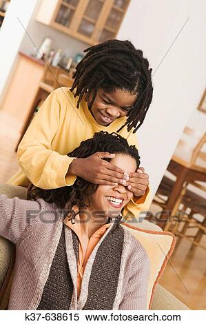 African American family at home, parents on sofa, son covering mother's eyes with hands from behind. Guess who? View Large Photo Image Stock Photography - African American family at home, parents on sofa, son covering mother's eyes with hands from behind. Guess who?. Fotosearch