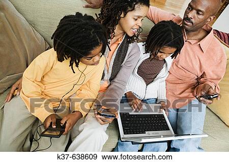African-American family at home using different technologies including laptop, pda, ipod, cell phone & gameboy. View Large Photo Image Stock Photo - African-American family at home using different technologies including laptop, pda, ipod, cell phone & gameboy.. Fotosearch