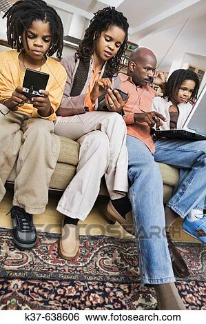 African-American family at home using different technologies including laptop, pda, ipod, cell phone & gameboy. View Large Photo Image Stock Photograph - African-American family at home using different technologies including laptop, pda, ipod, cell phone & gameboy.. Fotosearch