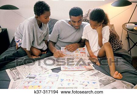 African-American father and children reading newspaper's comics View Large Photo Image Picture - African-American father and children reading newspaper's comics. Fotosearch