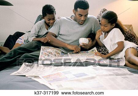 Stock Photo - African-American father and children reading newspaper's comics. Fotosearch