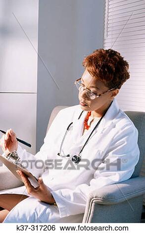 African-American female medical doctor looking over patient's health chart View Large Photo Image Stock Photograph - African-American female medical doctor looking over patient's health chart. Fotosearch