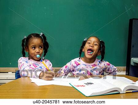 Stock Image - African American twins doing homework.. Fotosearch