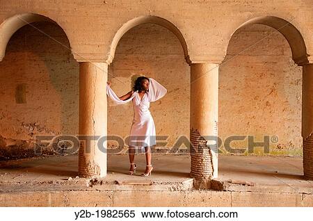Stock Photography - African American woman wearing white dress standing in front of columns of automobile tunnel in urban Memphis Tennessee USA.. Fotosearch