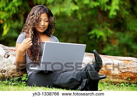 African American young woman using a laptop while sitting on a grass View Large Photo Image Stock Photograph - African American young woman using a laptop while sitting on a grass. Fotosearch