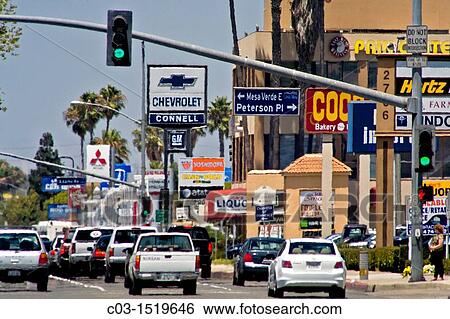 Stock Photograph - Afternoon traffic passes retail advertising signs in Costa Mesa, CA Note haze from summer heat. Fotosearch
