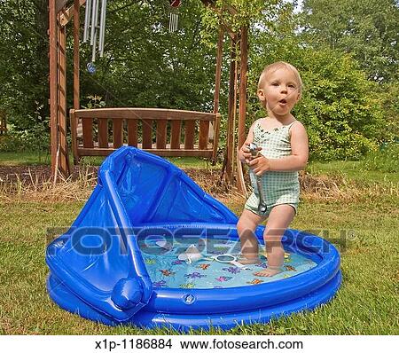 Picture - Age eighteen months, Attractive, Backyard, Bathing suit, Blond hair, Blow up pool. Fotosearch