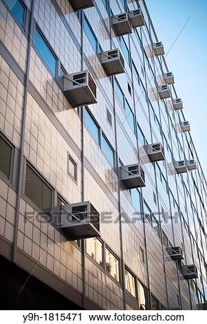 Stock Image - Air conditioners sprout from windows in a building in New York Attractive pricing and smuggling of the illegal coolant HCFC-22 freon is making it difficult to phase it out. Fotosearch