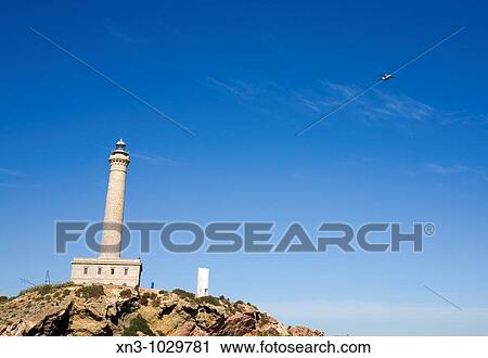 Stock Image - Airplane flying Lighthouse. Cabo de Palos. La Manga. Mar Menor. Cartagena. Murcia. Spain.. Fotosearch