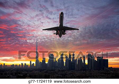 Stock Photo - Airplane leaving a city at sunset. United Arab Emirates. Dubai.. Fotosearch