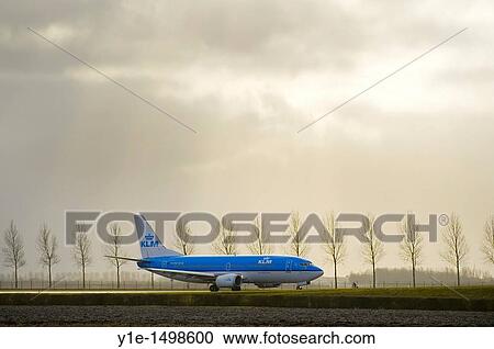 Stock Image - Airplane taxiing and man on a bicycle at Schiphol Airport Amsterdam. Fotosearch