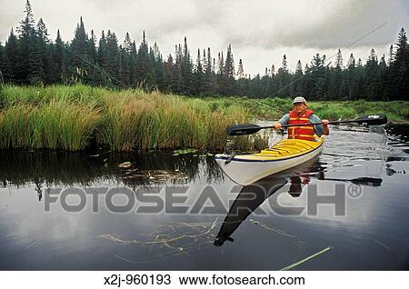 Stock Image - Algonquin Provincial Park, Ontario Canada - John West kayaking on the Tim River MR. Fotosearch