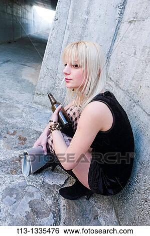 Stock Photograph - Alone with an empty bottle young woman. Fotosearch