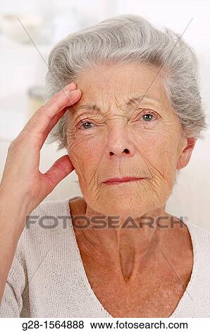 Stock Photo - ALZHEIMER, senior woman holding her forehead and trying to remember her souvenirs, or suffering from a headache. Fotosearch